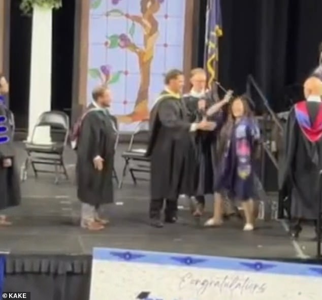 Graduates forced into awkward handshakes during chaotic Kansas high school ceremony.