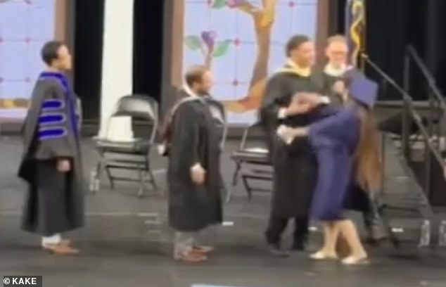 Graduates forced into awkward handshakes during chaotic Kansas high school ceremony.